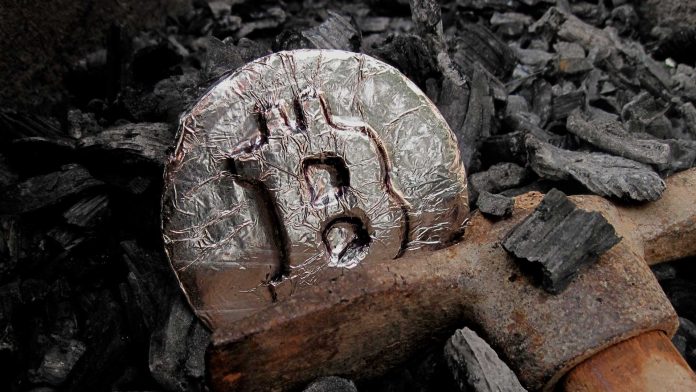 moneda de bitcoin plateada entre carbon