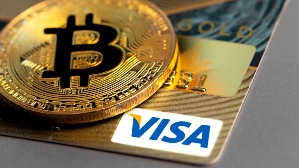 Tarjeta de Visa y moneda de Bitcoin.