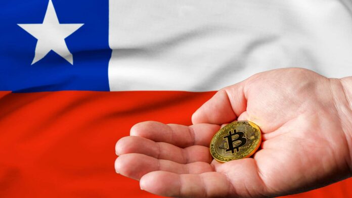 Moneda de bitcoin junto a bandera chilena.